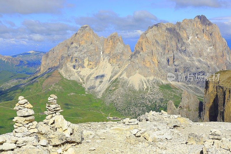 Inukshuk堆叠的石头之上的田园诗Sas Pordoi和Passo Sella, Langkofel顶峰山丘山脉正面观看日出，戏剧性的全景和雄伟的Dolomites，意大利泰洛阿尔卑斯山